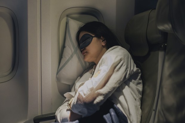 With her mask on to help her sleep, the woman gets good, deep sleep during her flight.