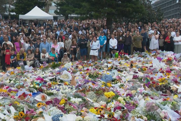 Mourners gather at a menorah lighting ceremony at a floral memorial for victims of Sunday's shooting, at the Bondi Pavilion.