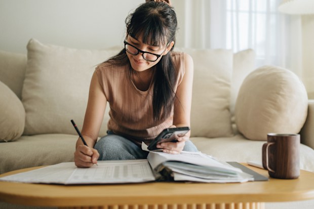 Stock image of a young woman sitting on her lounge and looking at her budget