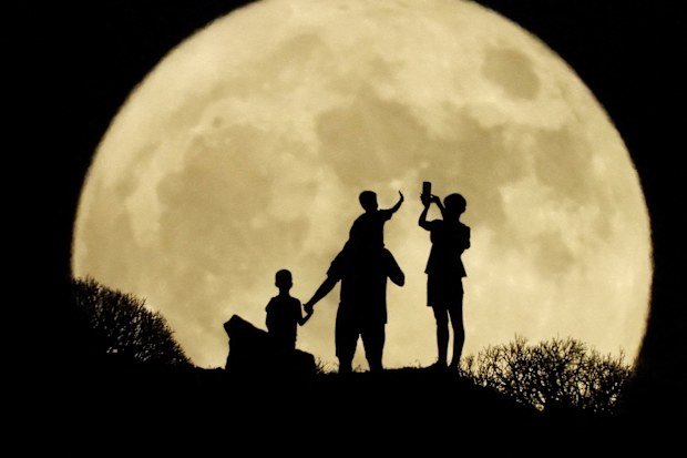 A family stand with the full moon known as the "Sturgeon Moon"