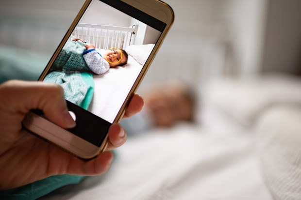 Parent taking photo of a baby with smartphone.