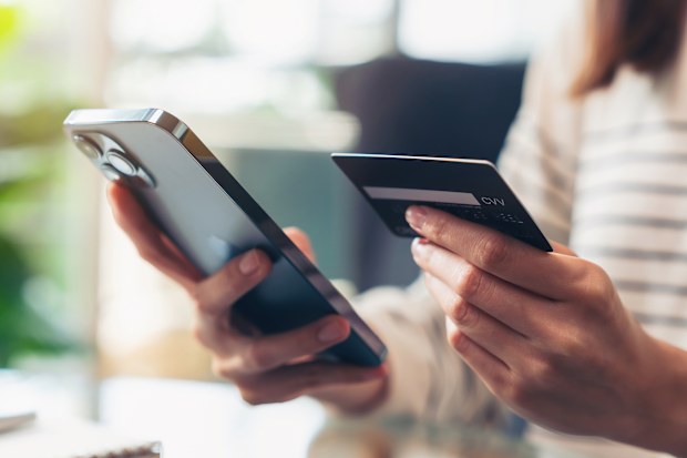 Stock image of a woman holding her phone and credit card