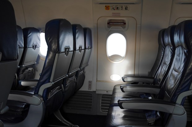 Empty airplane seat and window. Aircraft exit door. Emergency use only.