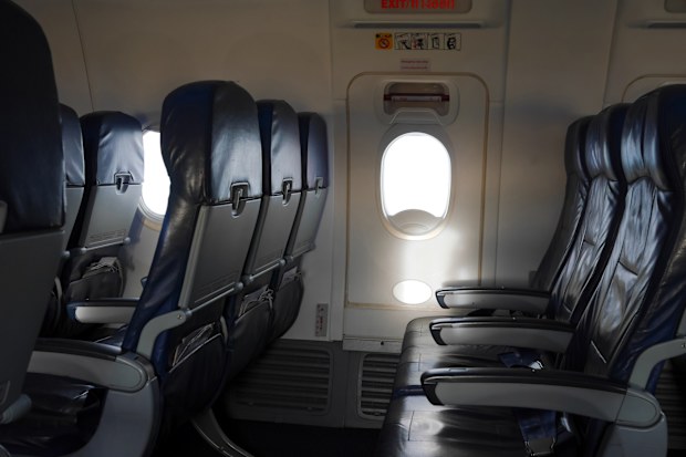Empty airplane seat and window. Aircraft exit door. Emergency use only.