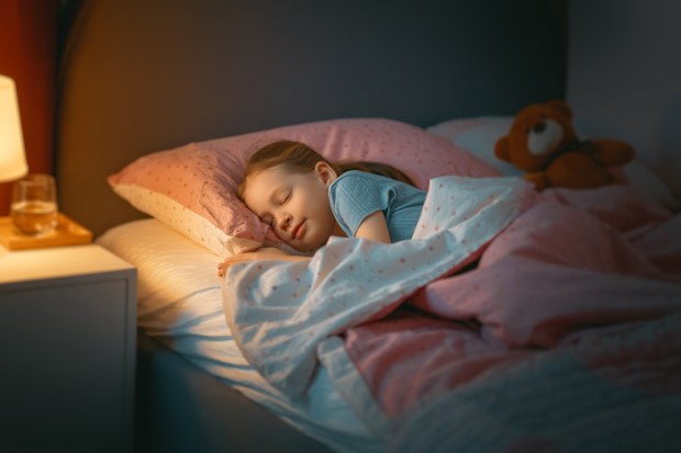 Adorable little child is sleeping in the bed.