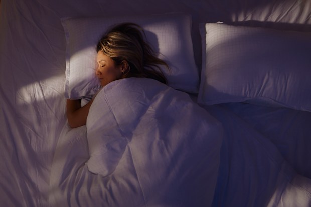 High angle view of a woman taking a nap in her bed at night.