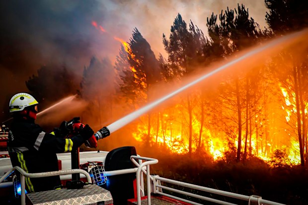 This photo taken on Friday July 15, 2022 by the fire brigade of the Gironde region (SDIS 33) shows firefighters using hose to fight a wildfire near Landiras, southwestern France, Thursday, July 14, 2022. 