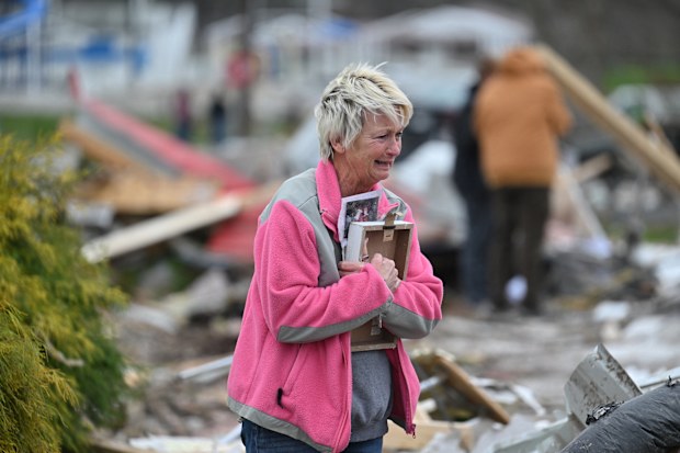 Debbie Lowdermilk holds photographs as she reacts while looking at the destroyed school she owns the day after a tornado hit Sullivan, Indiana, US April 1, 2023.  
