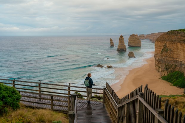 Man looking at Twelve Apostles Sea Rocks in Australia  during serene road trip in summer