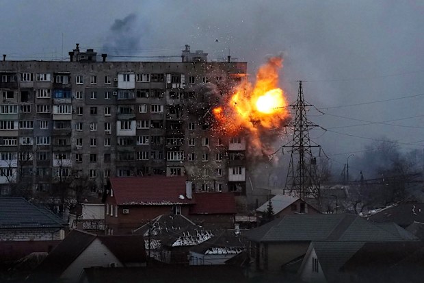 An explosion tears a hole in the side of an apartment building after a Russian tank fired a rocket in Mariupol, Ukraine.