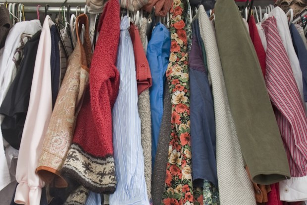 messy closet overfilled with colorful woman clothes on hangers and stuffed in any available space, need for declutter concept
