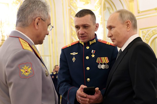 Russian President Vladimir Putin, right, talks with Russian Defense Minister Sergei Shoigu, left, and awarded Sgt. Nikolay Kharchenko after a ceremony to present Gold Star medals to Heroes of Russia on the eve of Heroes of the Fatherland Day at the St. George Hall of the Grand Kremlin Palace in Moscow, Russia, Friday, Dec. 8, 2023.