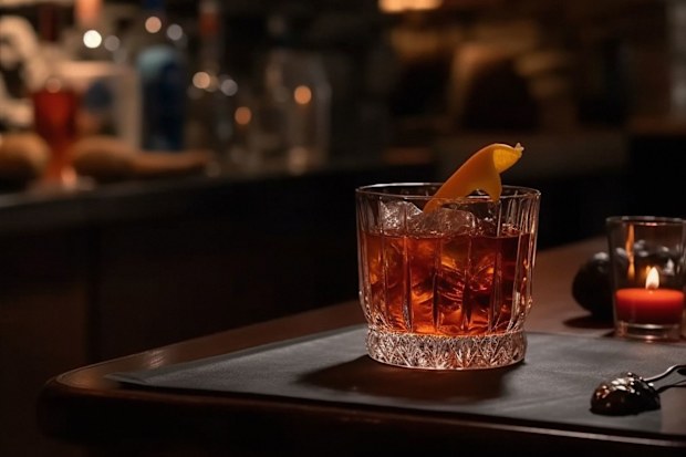 A crystal-clear whiskey drink in a rocks glass with a few cubes of ice, sitting on a dark bar countertop