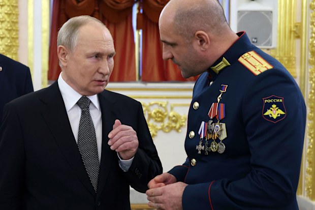 Russian President Vladimir Putin, left, speaks to commander of the reconnaissance battalion "Sparta" Artem Zhoga after a ceremony to present Gold Star medals to Heroes of Russia on the eve of Heroes of the Fatherland Day at the St. George Hall of the Grand Kremlin Palace, in Moscow, Russia, Friday, Dec. 8, 2023. 