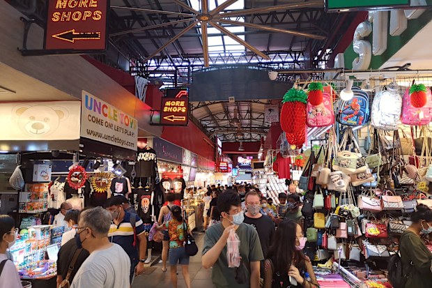 People walking by the stalls in Bugis street, a lively shopping street with dozens of apparel shops, food markets, souvenir stores & eateries in downtown Singapore.