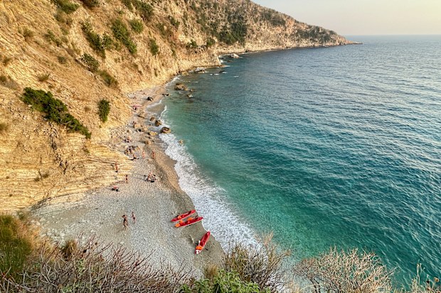 Aerial view of paradisiac Filikuri beach with red canoes and turquoise blue water in Himare, Albania.