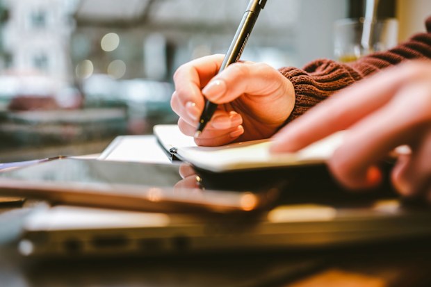 CNN STOCK IMAGE: Admin night is becoming the newest book club. person doing their life admin on a piece of paper. Bills, taxes, 