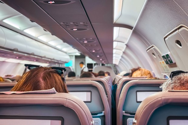 Airplane cabin during flight. Passengers and cabin crew. Shallow DOF, selective focus.