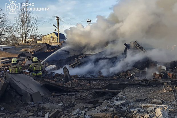 emergency services personnel work to extinguish a fire following a Russian rocket attack in Lviv, Ukraine, Sunday, Nov. 17, 2024 