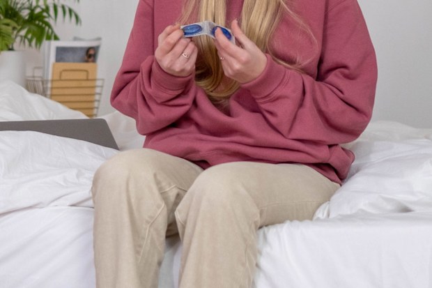 Stock photo of a woman on her bed with condoms.