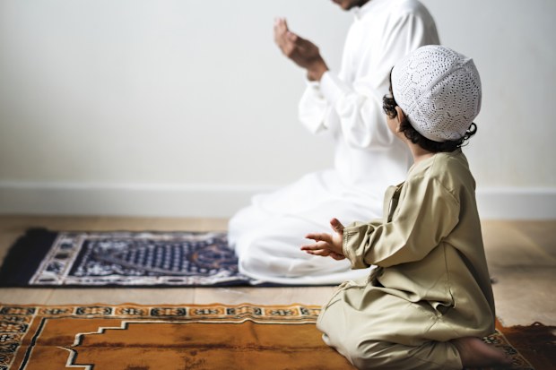 Little boy praying alongside his father during Ramadan Eid Muslim Islam