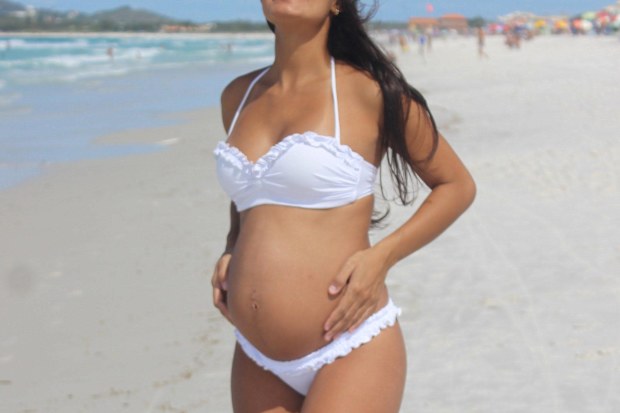 Stock photo of a pregnant woman in a bikini at the beach.