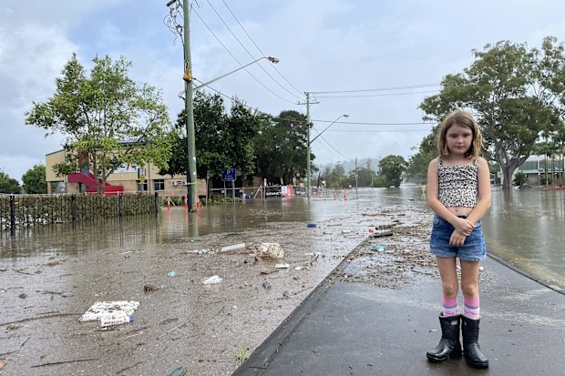 Ella Buckland's daughter stands on a flooded street in Lismore.