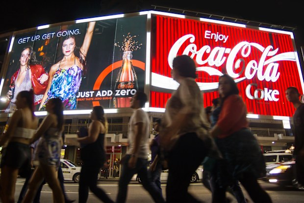 Sydney, Australia - March 22, 2014: A large group of people walk past two large neon Coca-Cola billboards on Kings Cross at night. First erected in 1974, the billboards have always featured Coca-Cola advertising and have become a prominent local landmark.