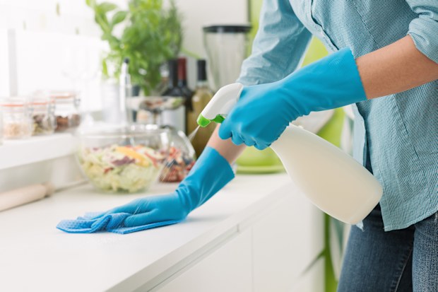 Woman cleaning and polishing the kitchen worktop with a spray detergent, housekeeping and hygiene concept