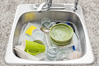 Dishwashing. Bright dishes soaking in the kitchen sink. Hand washing dishes, washing up, doing dishes by hand, soapy water in kitchen sink