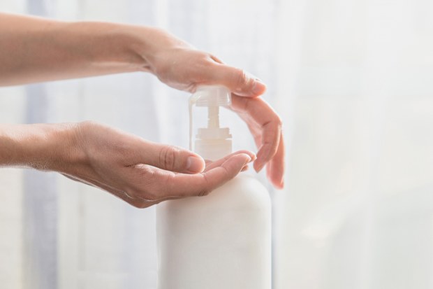 Woman hands pushing pump plastic soap bottle
