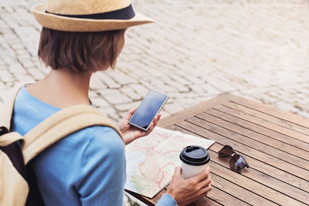 Young woman using phone in a cafe, travel concept