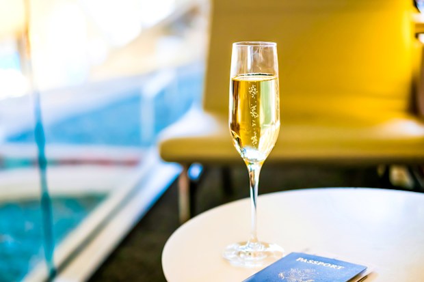 Glass of champagne and passport on white table in business lounge zone in airport.