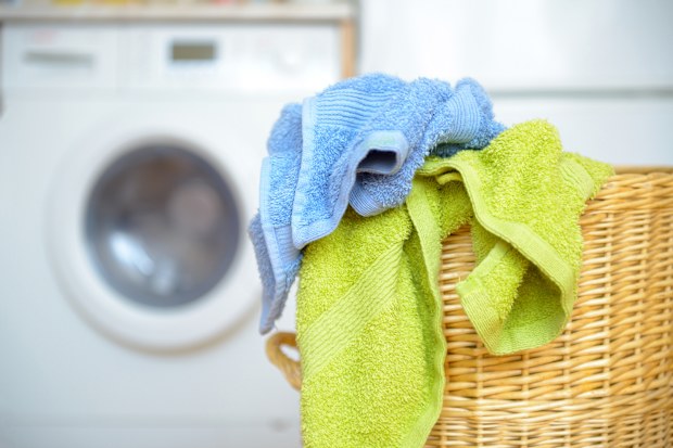 Dirty clothes basket with towels waiting for laundry with washing machine in backround