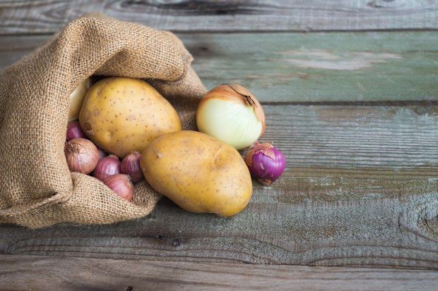raw potato shallots and onion in canvas bag on wooden