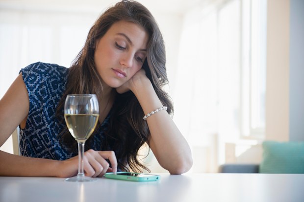 Woman looking at phone with glass of wine