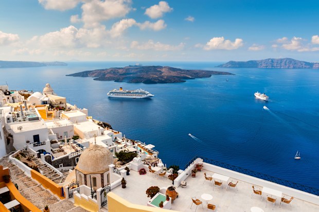 Santorini, Greece - 20th September 2012: Wide angle view of the cliff side buildings and large cruise ships in Santorini, Greece. Santorini is a small Greek island and popular holiday destination.