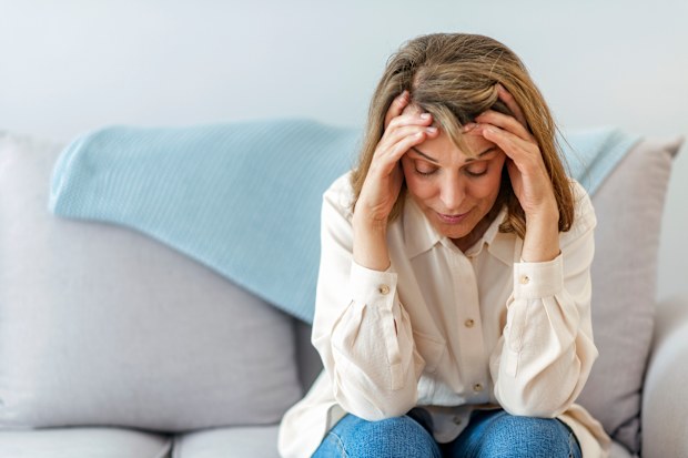 Woman with head in hands. Woman with headache. Sick woman. Sad woman. Sad older woman.