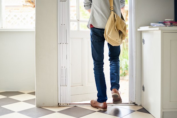 Rear view of an unrecognizable young man walking out through a door in his kitchen at home