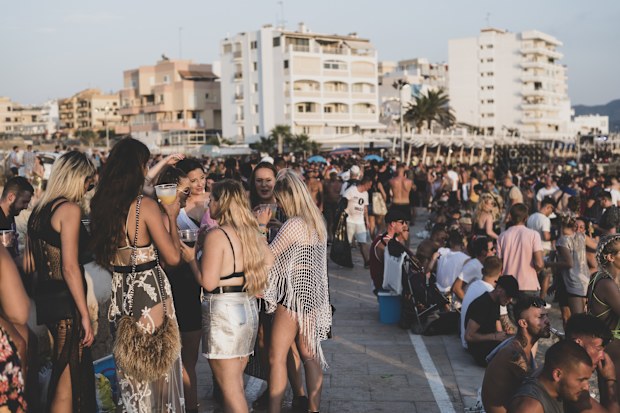 A large crowd of mostly young adults gathers for sunset at the beach on the 'sunset strip' in San Antonio, Ibiza. (August 3, 2018)