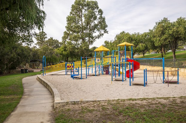 Outdoor park area featuring vibrant playground structures, surrounded by greenery and walking paths. Ideal setting for children's recreation, community activities, and relaxation amidst nature's beauty