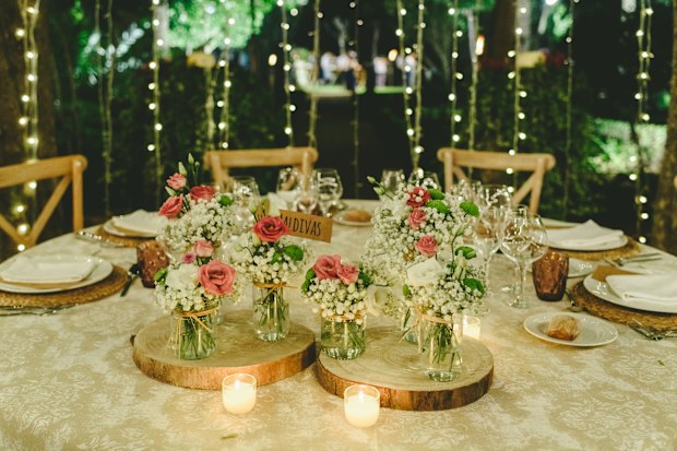 Outdoor tables for an elegantly decorated wedding reception, with lovely floral centerpieces and vintage style tableware and cutlery.