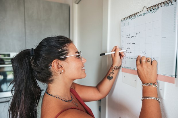 Woman takes note on the kitchen calendar at home.