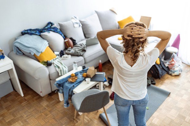 Woman looking at her messy loungeroom, cleaning