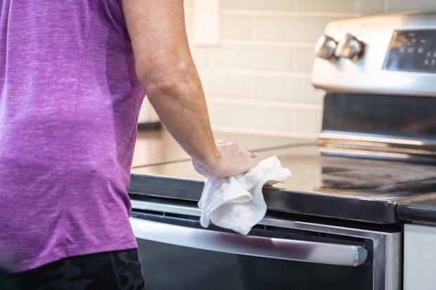 A woman is polishing a glass-ceramic stove top
