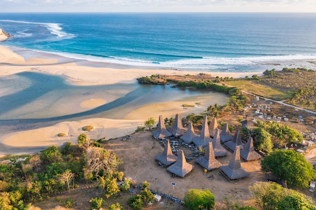 Aerial drone view of the village of Ratenggaro with the traditional houses and beautiful sea coast during sunset at the western site of Sumba island, Indonesia.