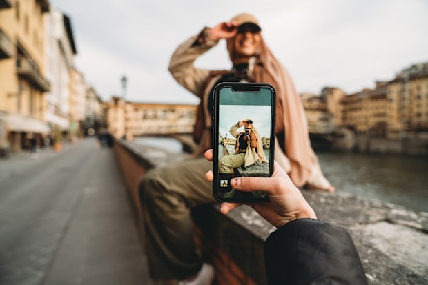 A young adult woman is taking a picture to her friends. They are sharing their travel on social media. Pov view.