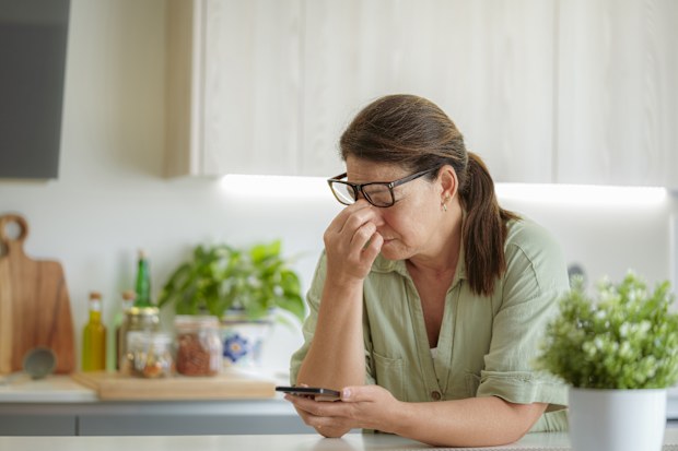 Tired woman suffering eyestrain using phone. Massaging her nose