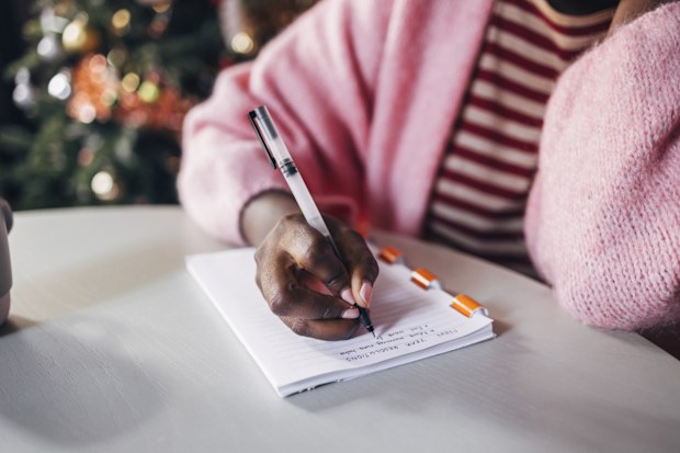 Close up shot of an anonymous woman writing plan for a New Year on a Christmas day.