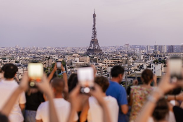 Crowd of tourists taking photos of the Eiffel. They are waiting for dusk when lights on tower turning on